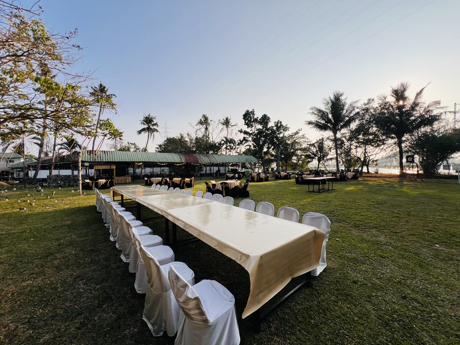 A long table set on the island lawn beside the backwater