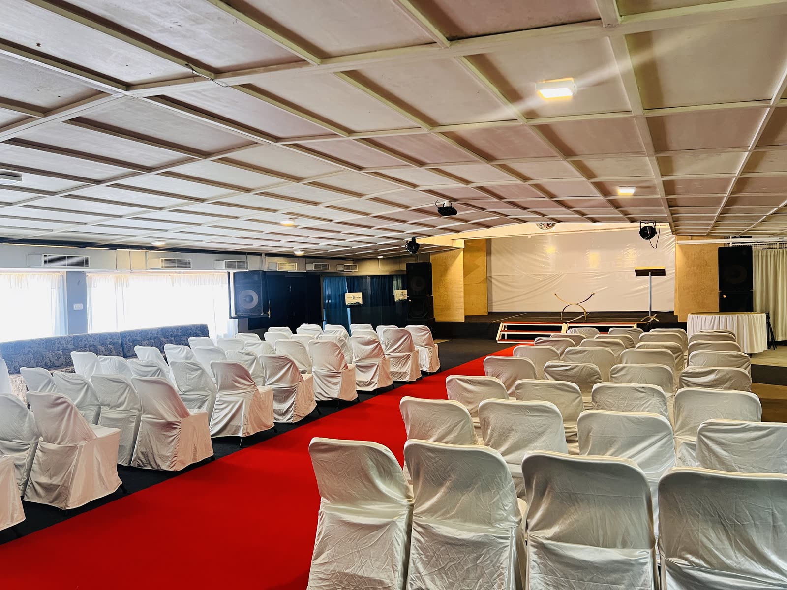 An air-conditioned hall set with rows of covered chairs facing a stage